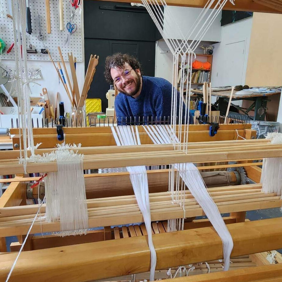 Artist Christian Dauble standing behind a multishaft floor loom